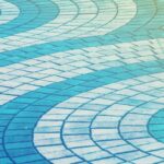 Curved blue and white paving tiles forming an abstract wave pattern on a walkway.
