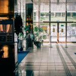 Elegant modern hotel lobby with glass entrance, luxurious design, and indoor plants.